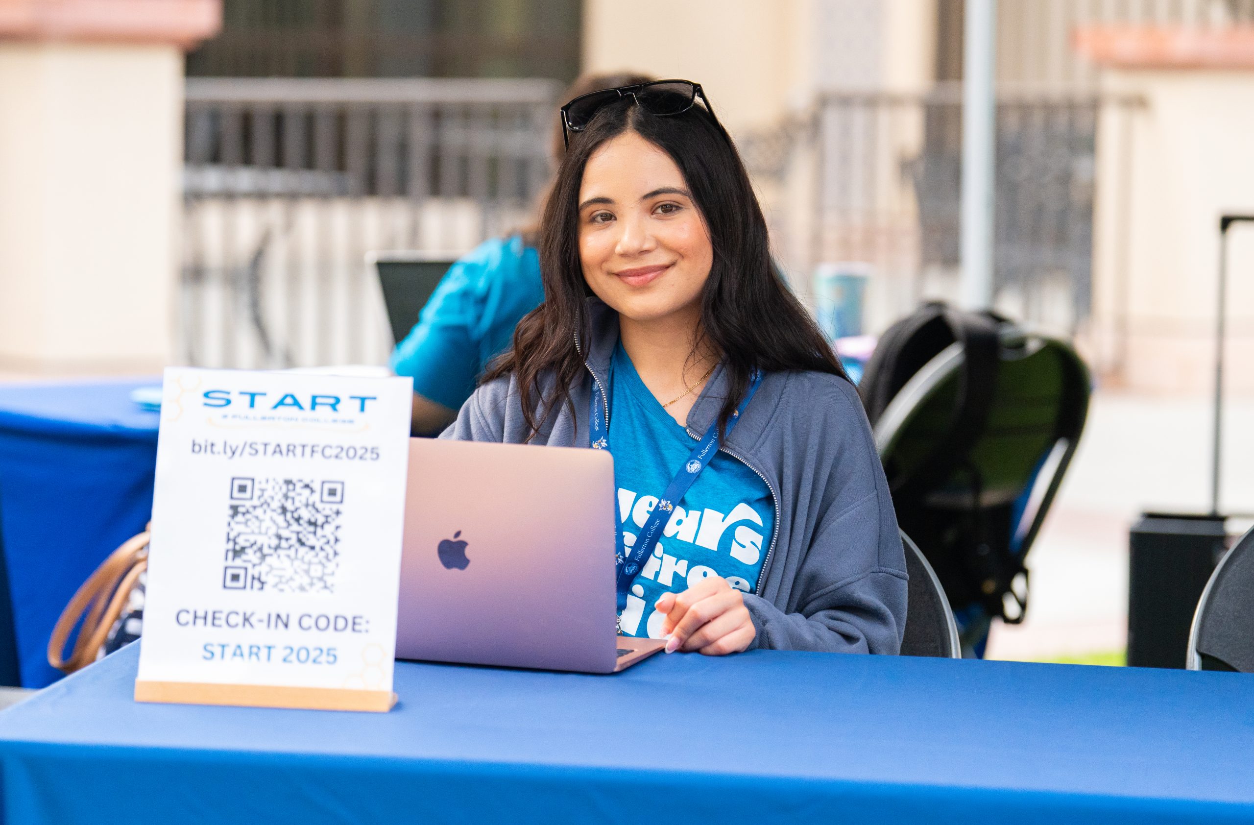 photo of a student hourly sitting and smiling at an information booth