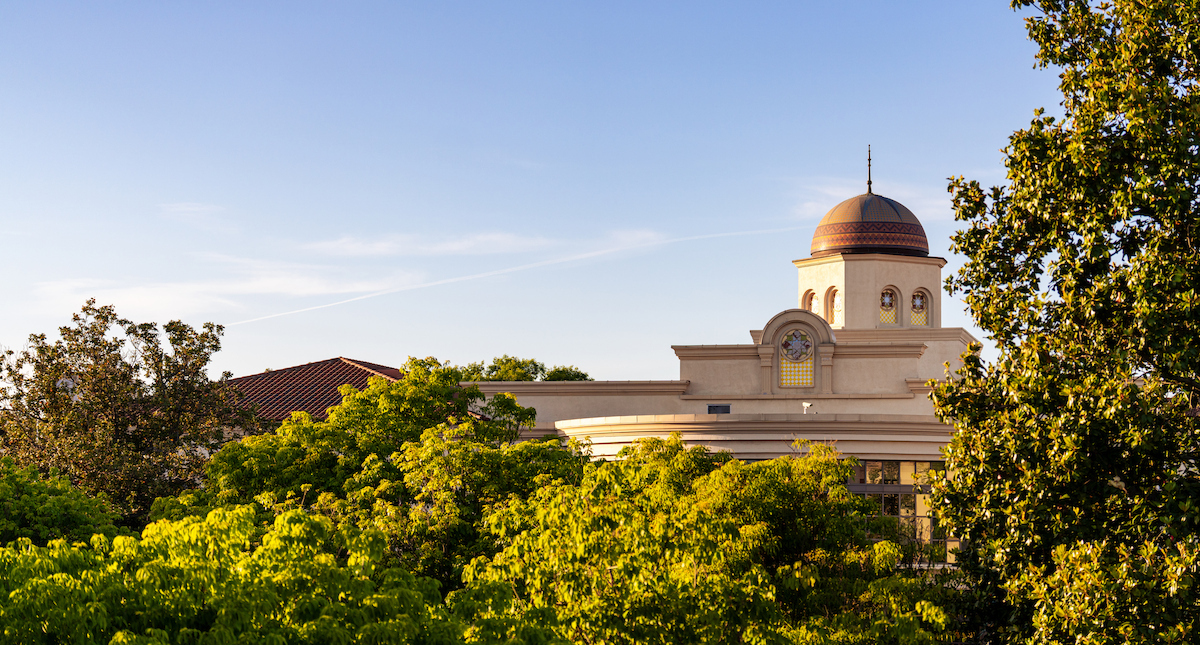 Library dome surrounded by trees during sunset.